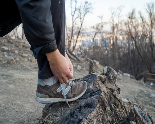 A person tying shoelaces before a comfortable brisk walk in nature